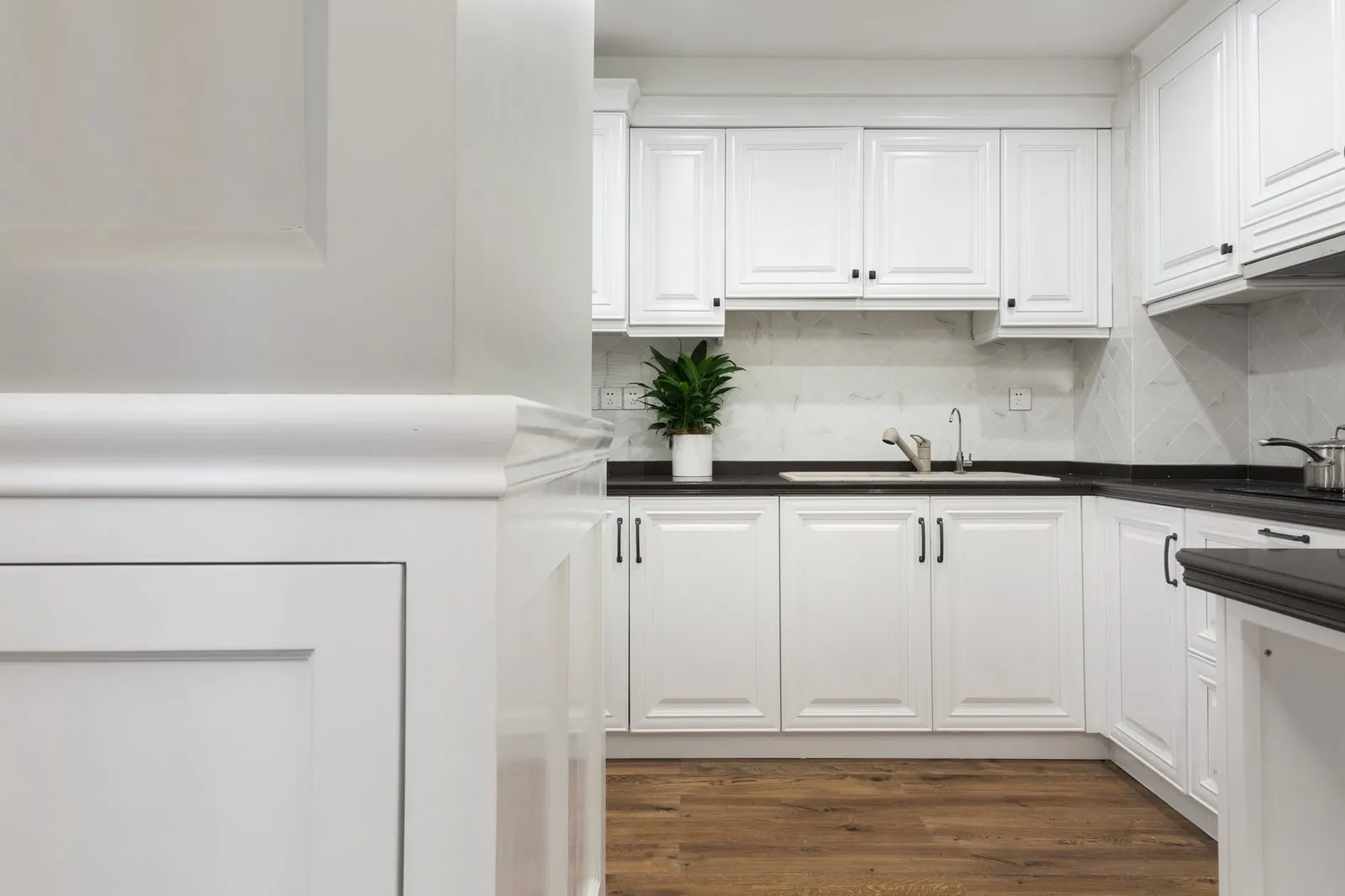 White shaker kitchen with a marble island and chandelier by Vamaylo